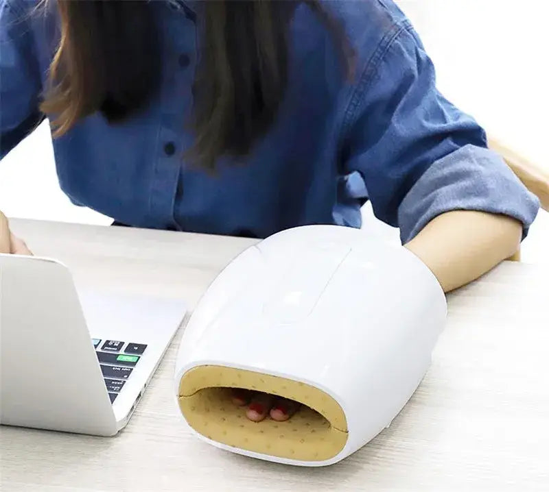 Electric hand massager with finger acupoint therapy next to a laptop for relaxation.