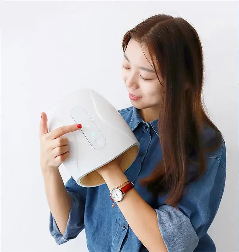 Young woman in denim shirt with electric hand massager for finger acupoint therapy.